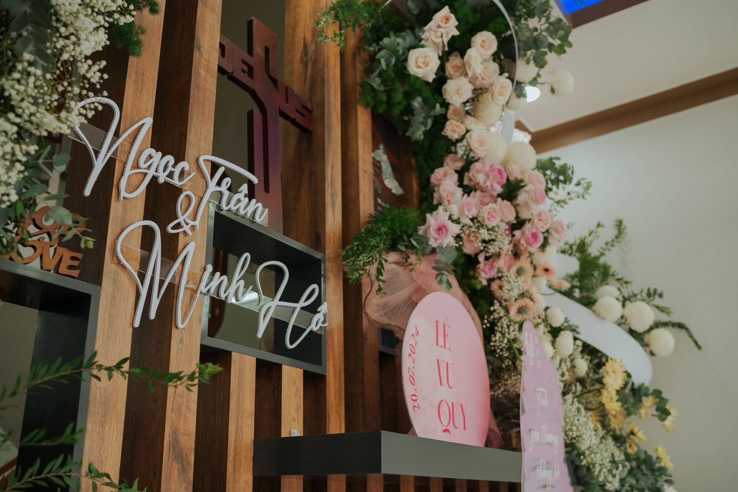 Decorative wooden wall with illuminated signage and pink floral arrangements.
