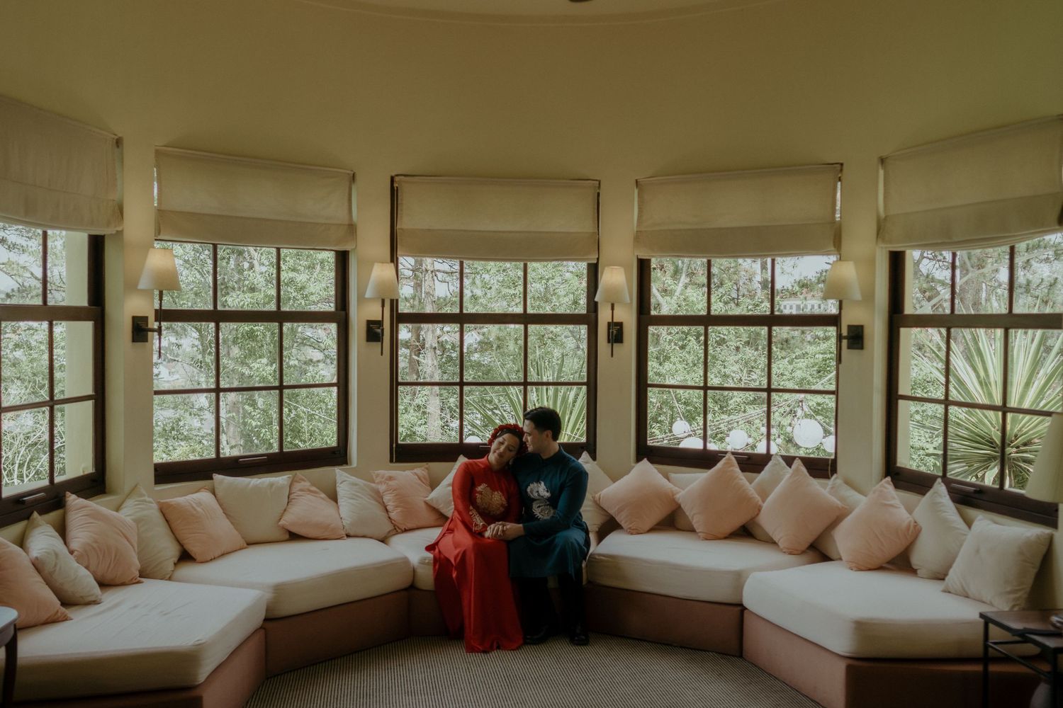 A cozy built-in window seat with plush cushions offers panoramic views of lush greenery through large windows.