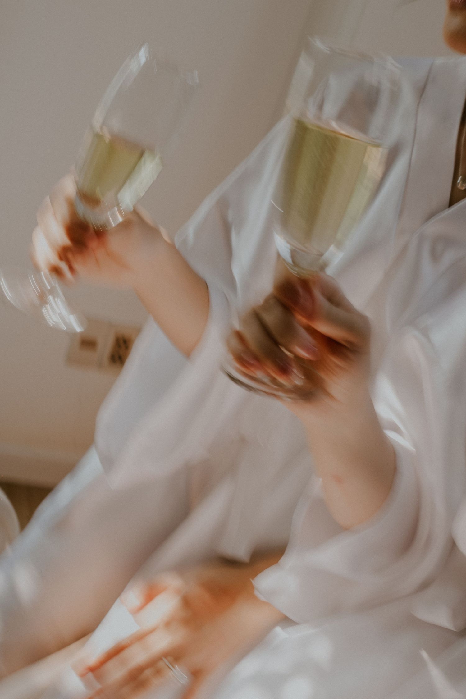 Close-up of hands holding champagne glasses filled with bubbly celebration drinks.
