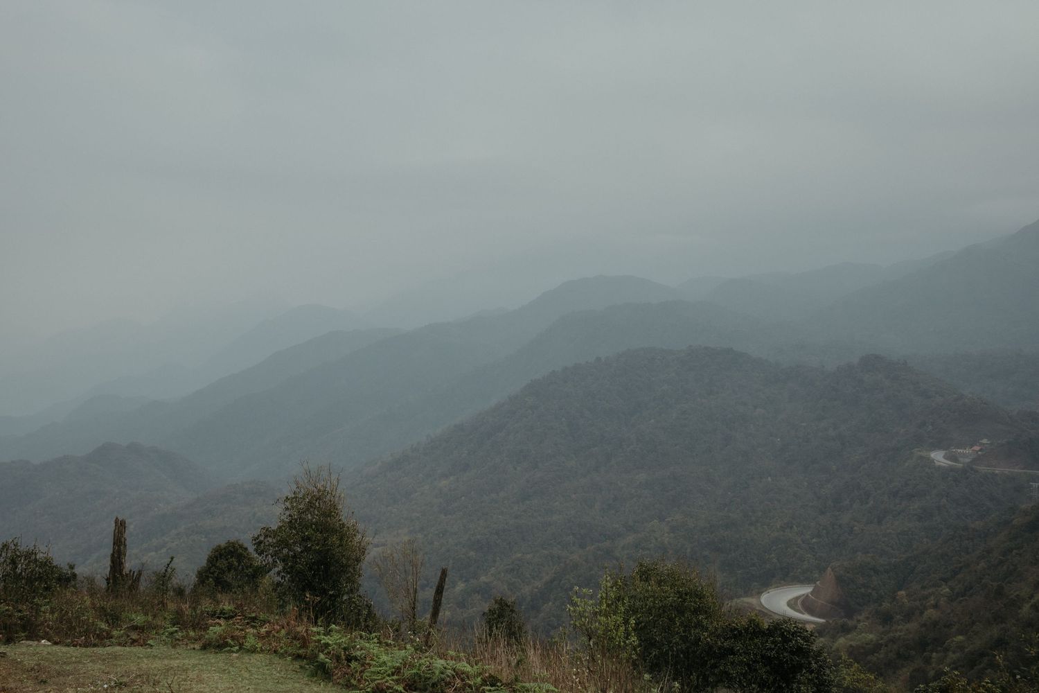 Misty mountain landscape with rolling hills and a winding road disappearing into the distance.