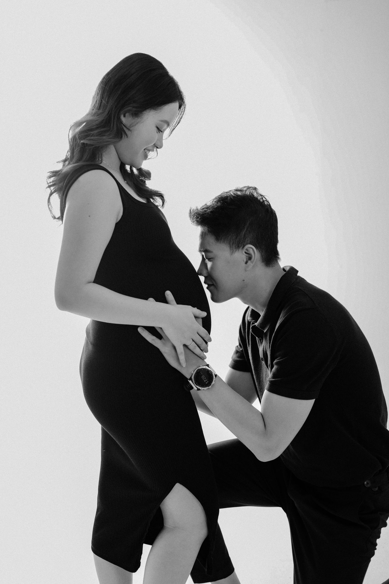 Black and white maternity photo showing tender moment between expectant parents.