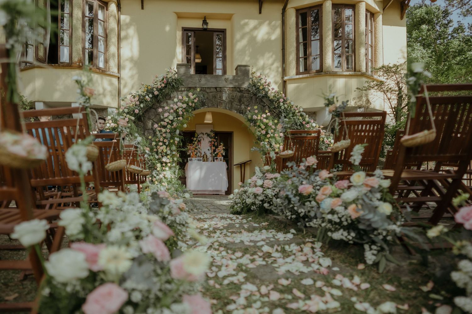 A romantic floral arch with pink and white flowers decorates the entrance of a vintage European-style villa.
