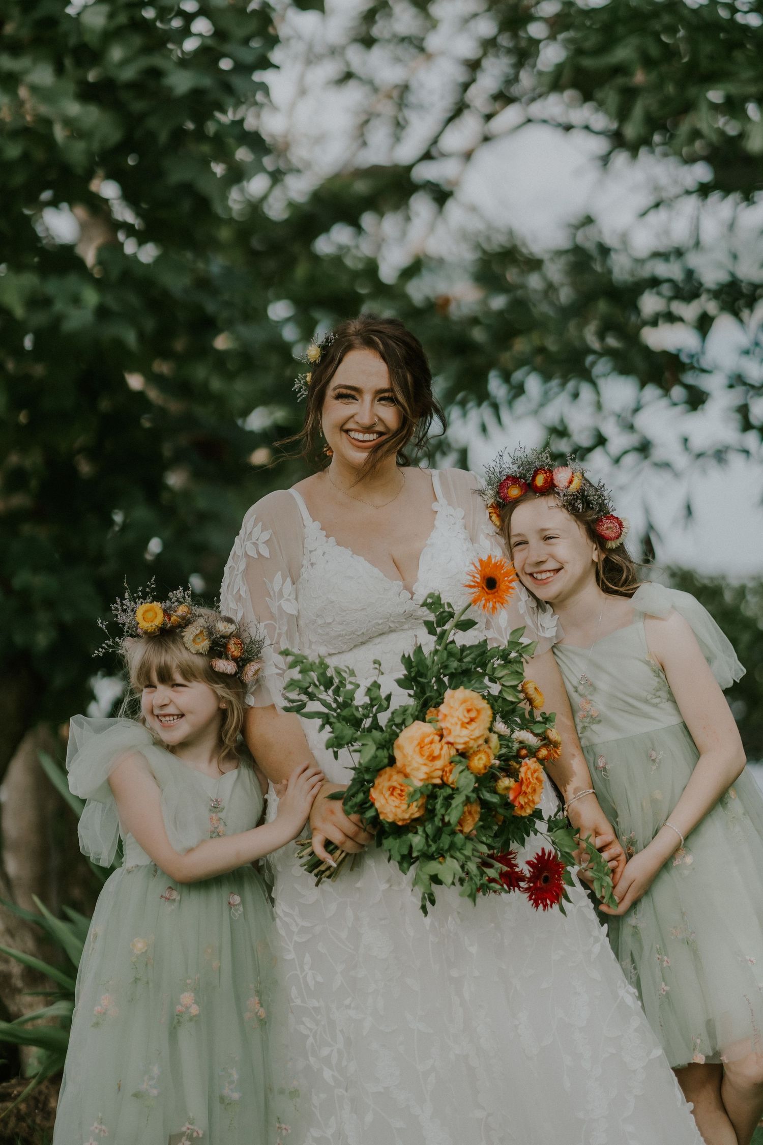 A heartwarming wedding portrait featuring mint green dresses and bright orange floral accents.