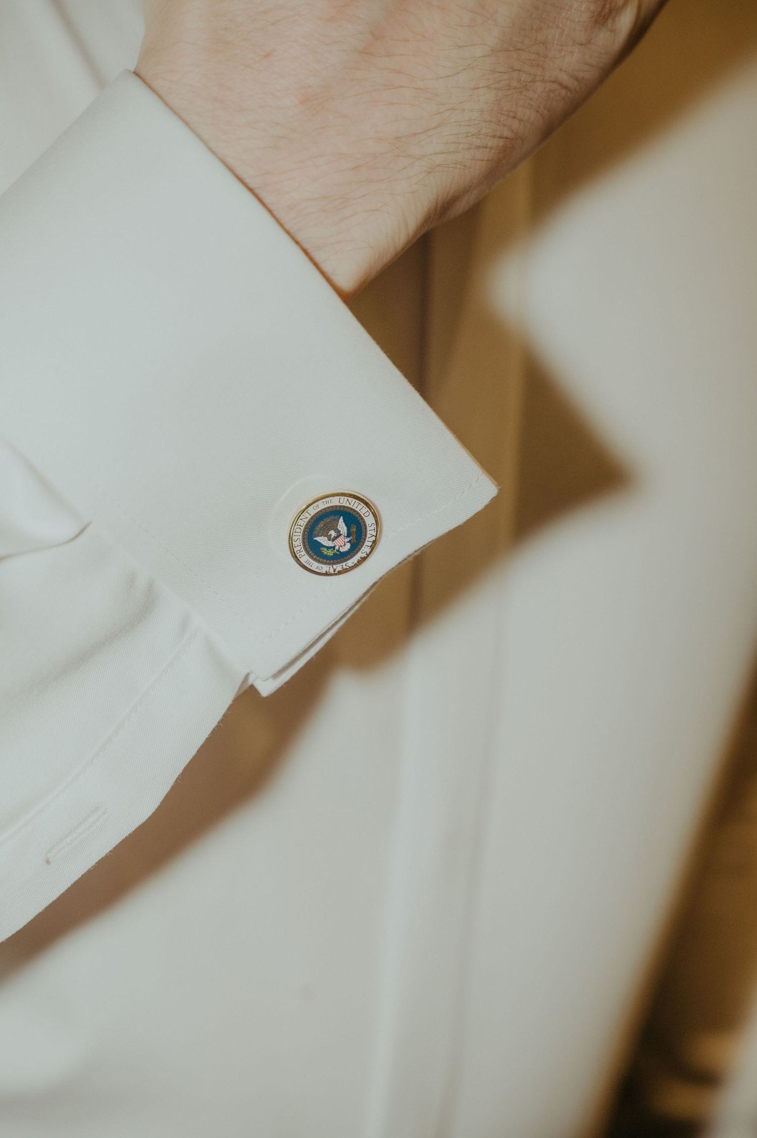 Close-up detail of a blue cufflink on a white dress shirt sleeve.