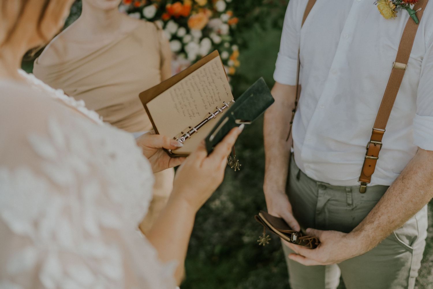 Hands holding a book during outdoor wedding ceremony with rustic attire.