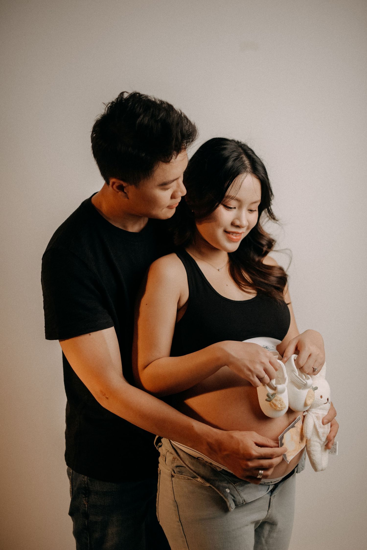 A tender maternity photo shoot with a couple in black clothing sharing an intimate moment.