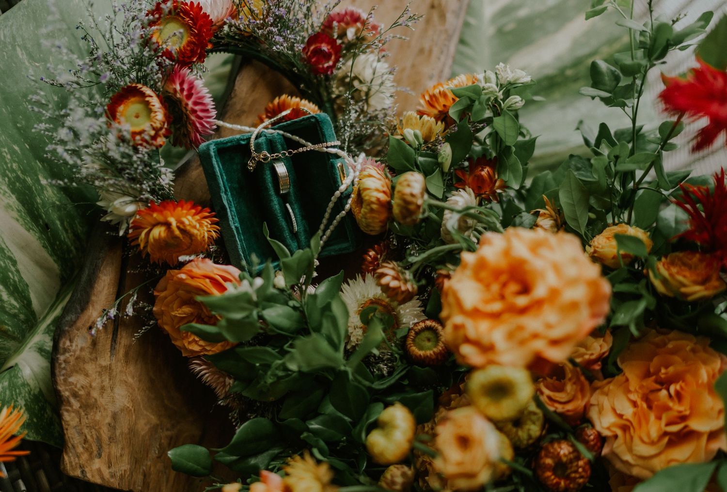 Close-up of vibrant orange and peach roses with turquoise accents in a lush floral arrangement.