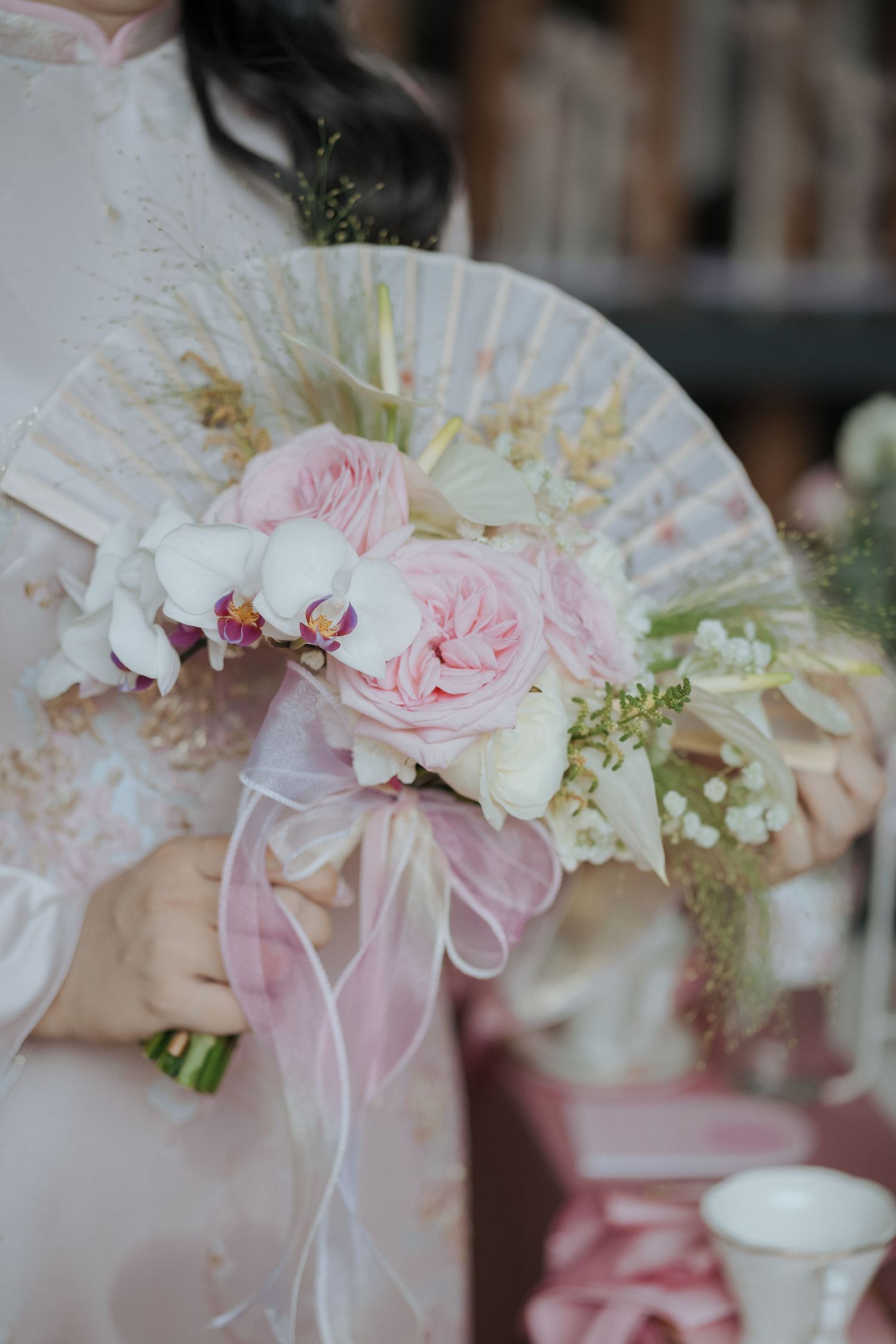 Elegant bridal bouquet with pink roses and white flowers tied with silk ribbon.