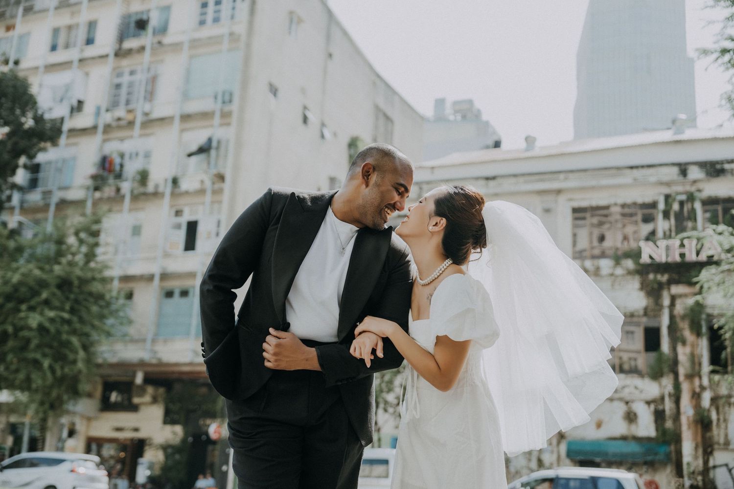 A couple shares a joyful moment together on a city street during their wedding.