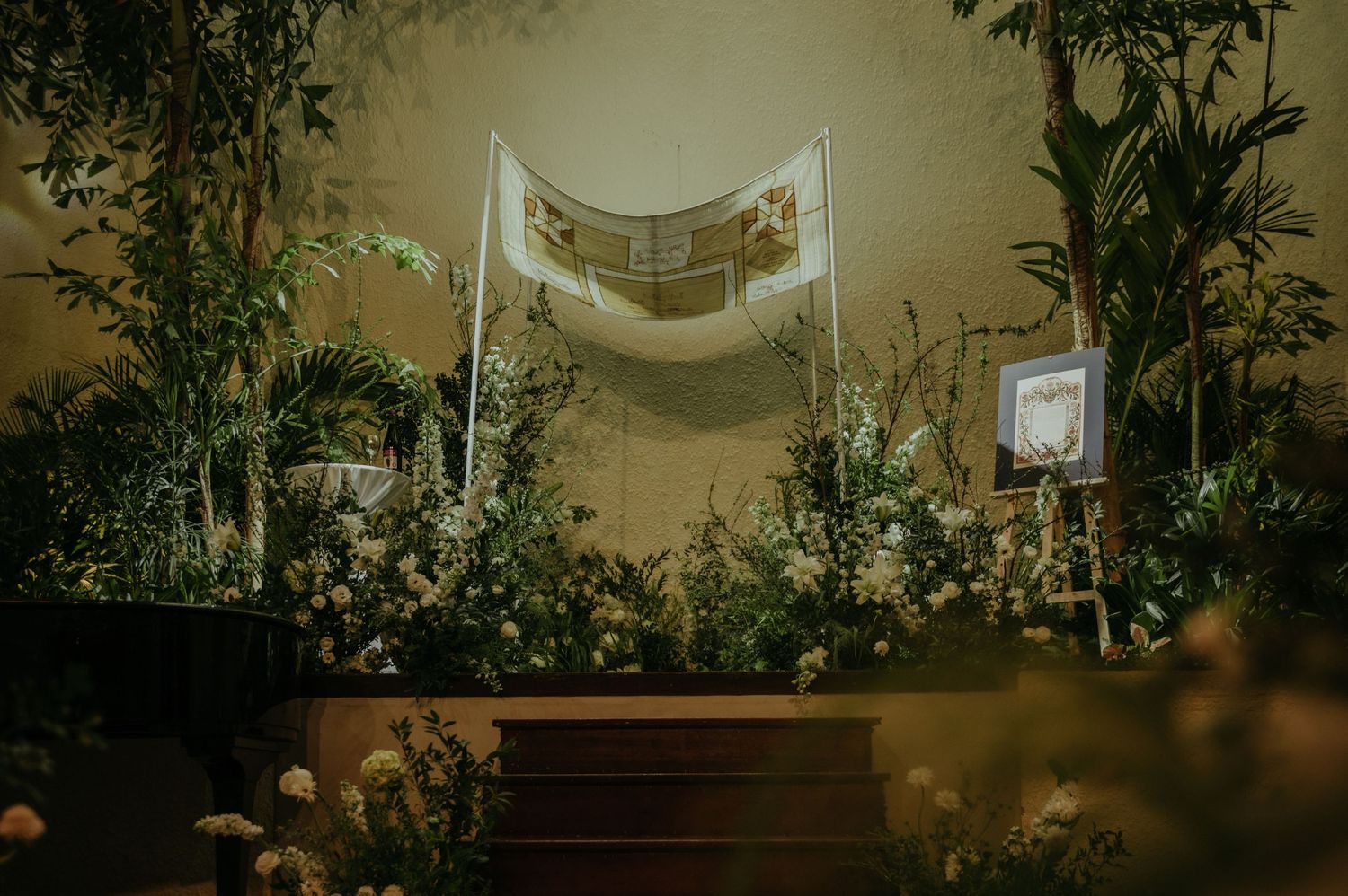 Wedding ceremony space decorated with white fabric draping and greenery.