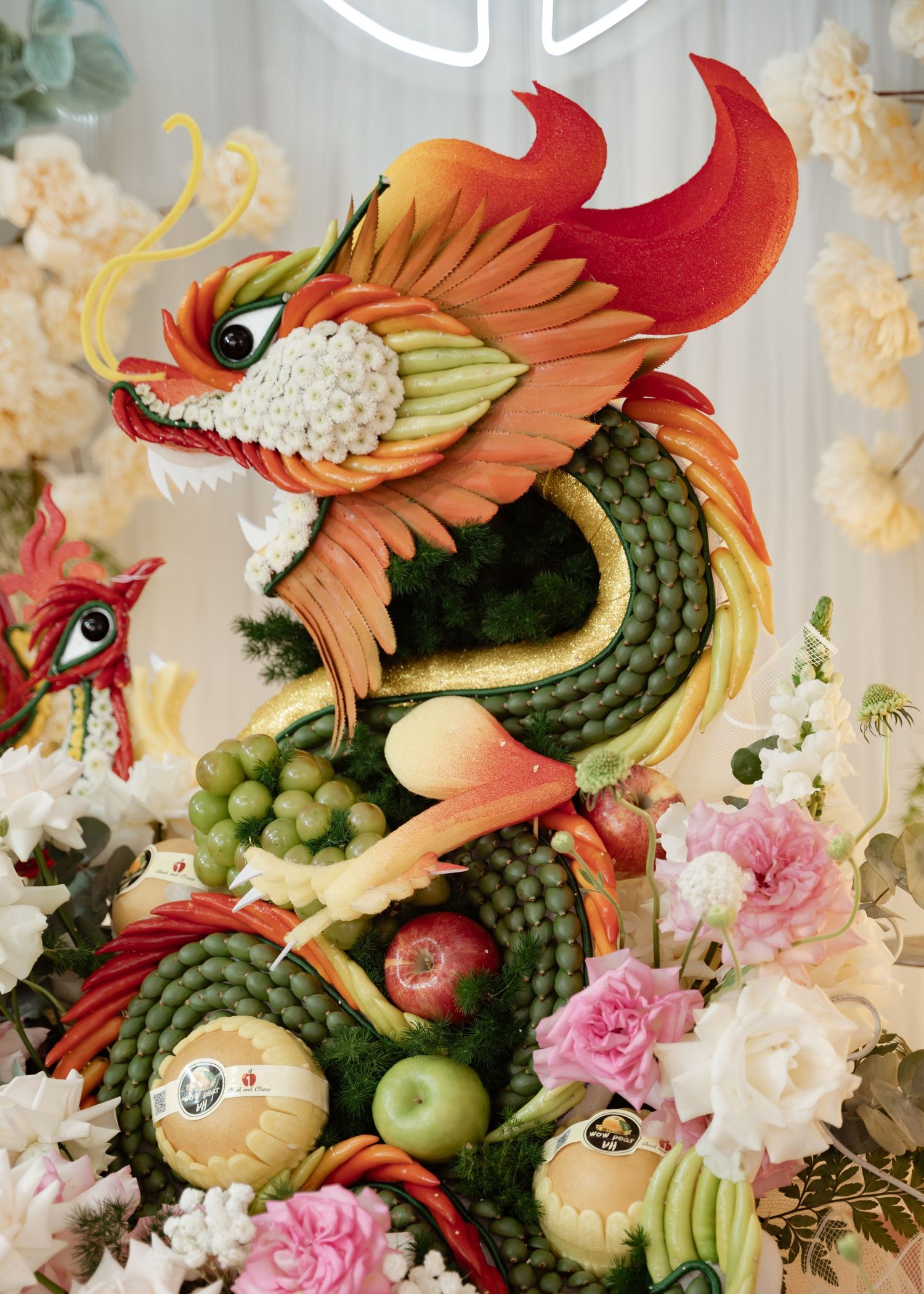 Artistic fruit and vegetable arrangement shaped like a dragon with ornate flowers, creating a stunning food sculpture display.