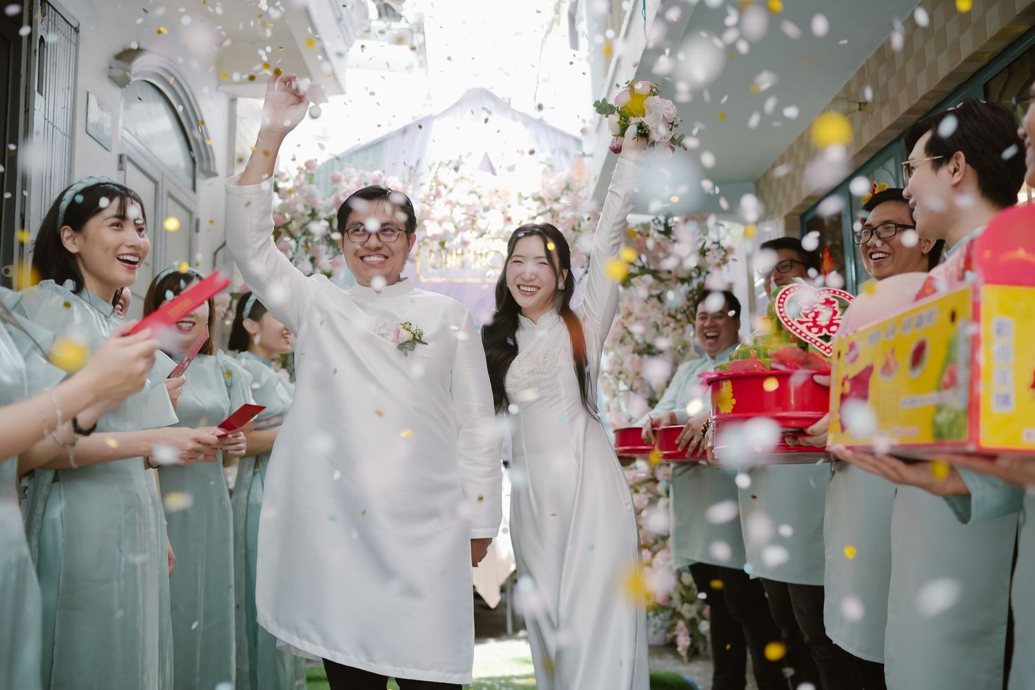 Wedding couple exits ceremony under umbrella while guests shower them with colorful confetti.