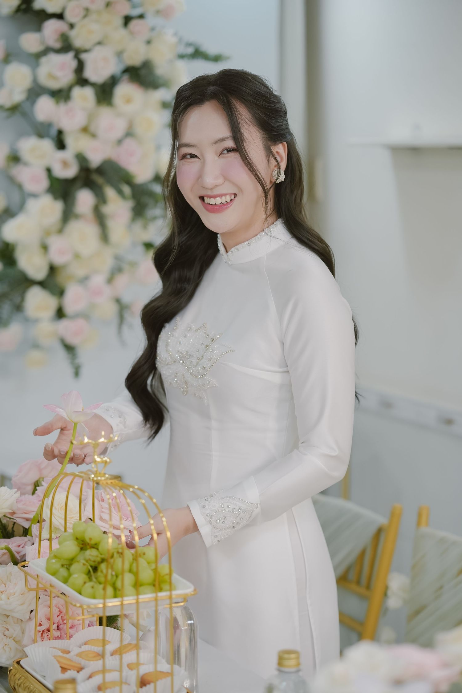Traditional white dress being showcased with gold birdcage and green grapes.