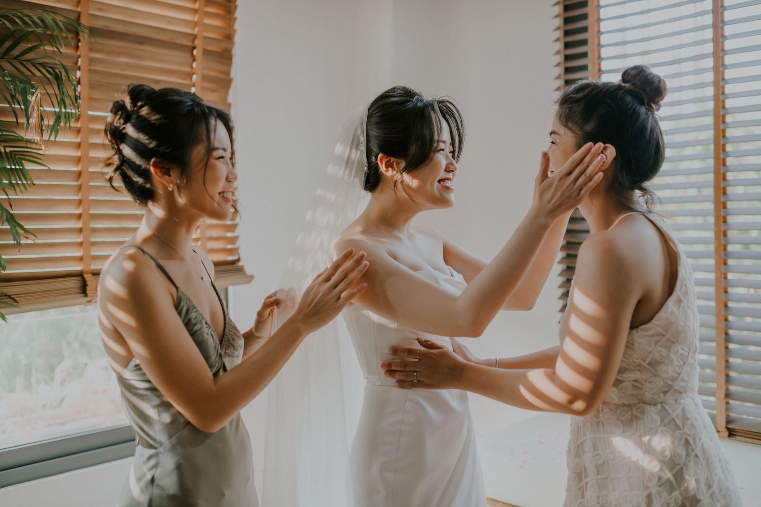 Emotional moment shared between people in formal attire by window with natural light streaming in.