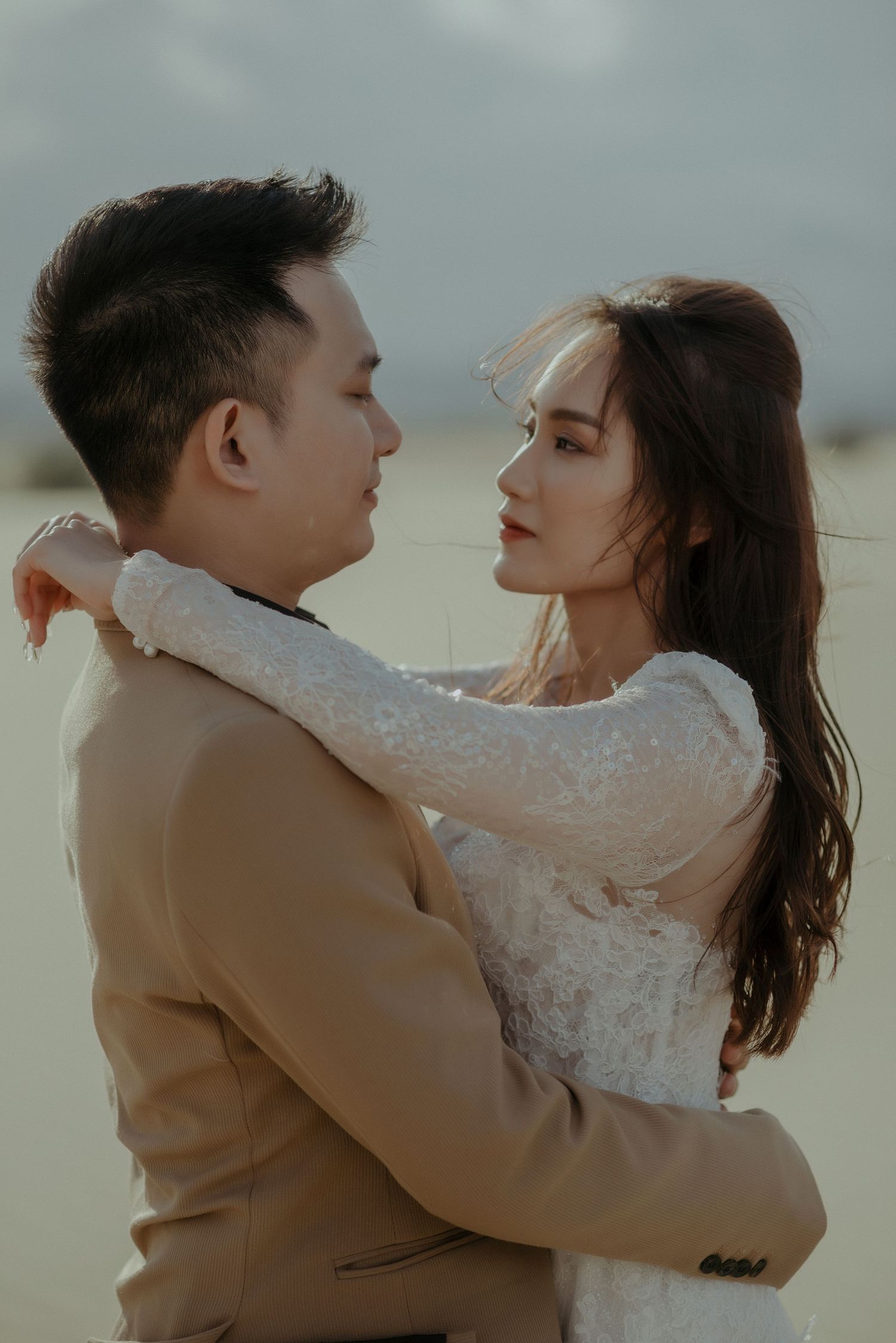 A romantic couple embraces in an intimate moment outdoors wearing formal attire during a golden sunset.
