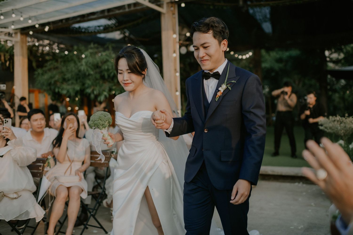 A celebration taking place on an outdoor patio with string lights and greenery.