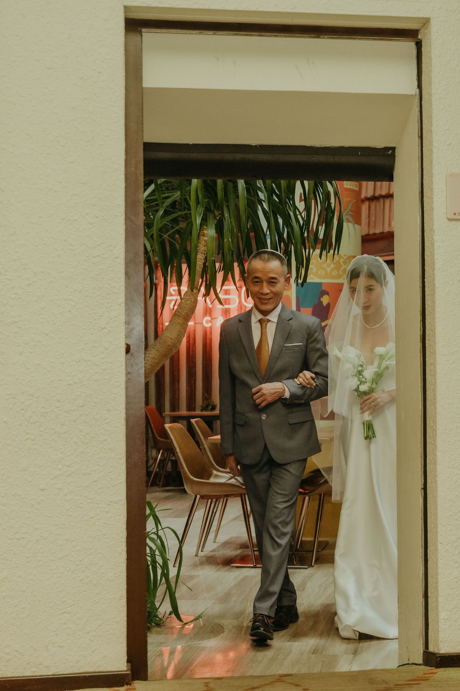 A couple entering through a doorway during a wedding processional.