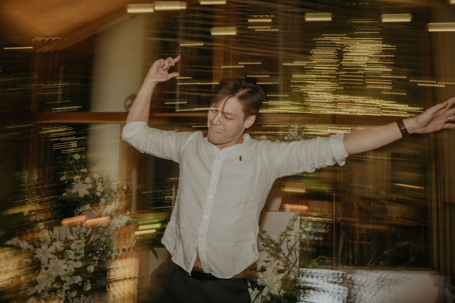 Guest dancing exuberantly with arms spread wide at an evening celebration.