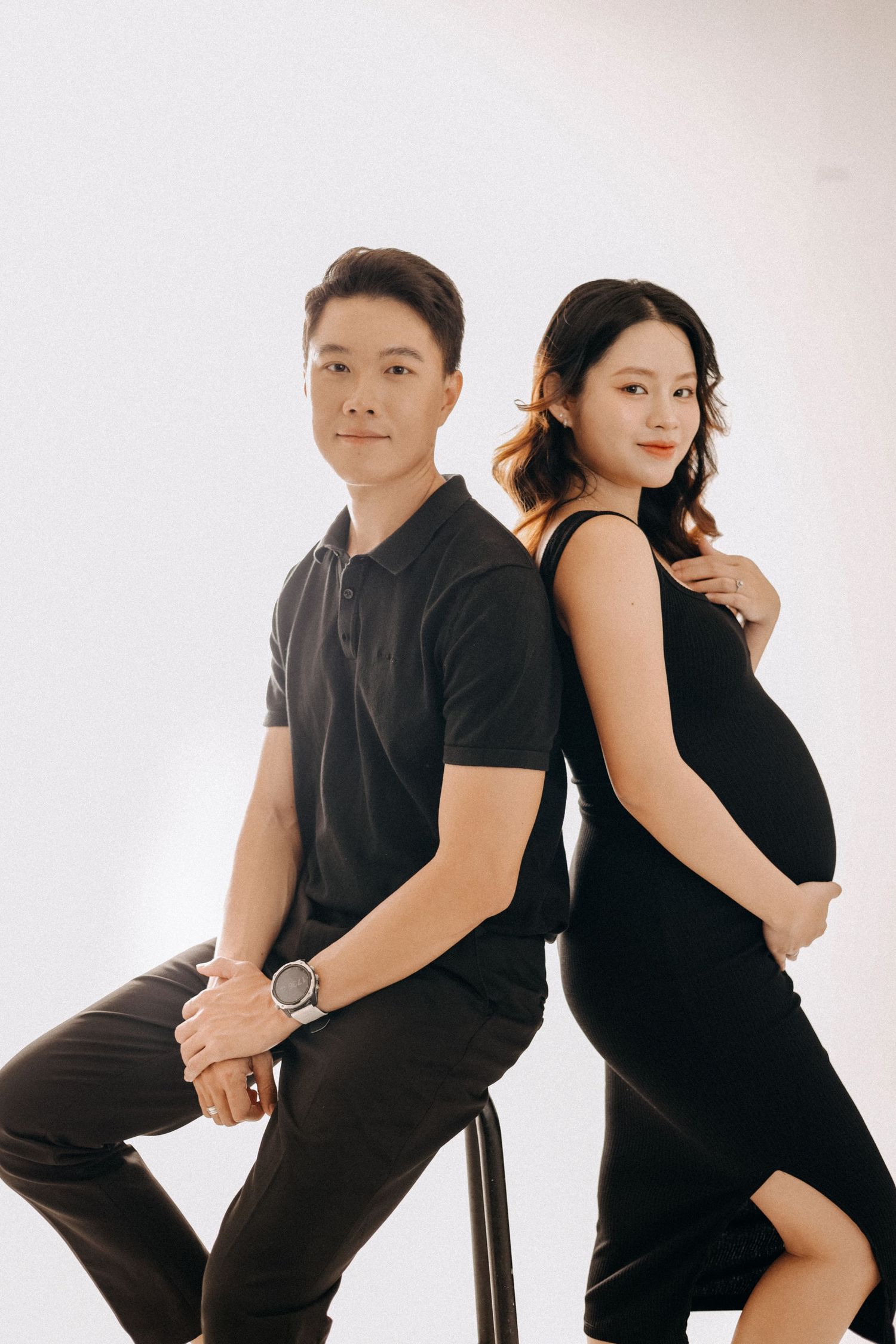 A stylish couple poses back-to-back during their maternity photo session.