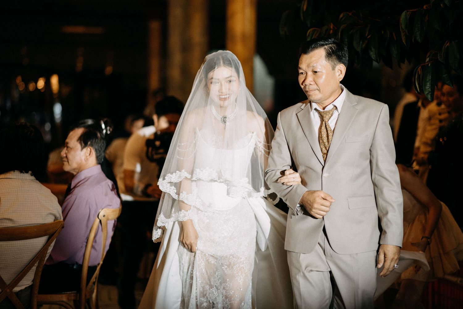 Traditional wedding ceremony processional in dimly lit indoor venue.
