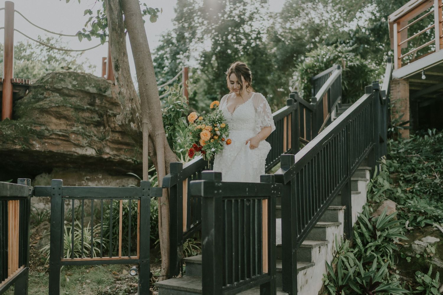 Garden wedding scene with decorative railings and natural stone backdrop.