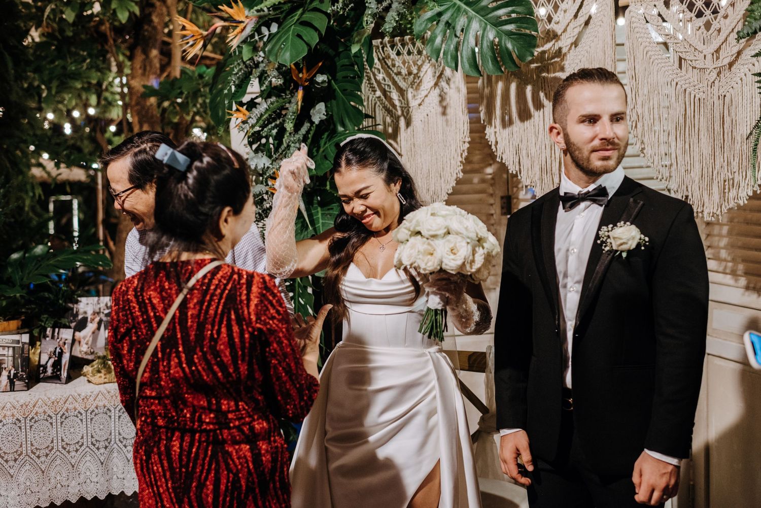 A reception celebration shows guests in formal attire with elegant tropical decor.