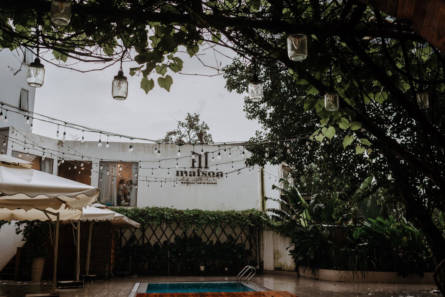 A rustic outdoor wedding venue with hanging mason jar lights and greenery.