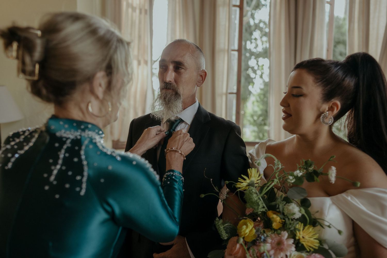 Wedding party gathered around bouquet with yellow flowers during an intimate indoor ceremony.
