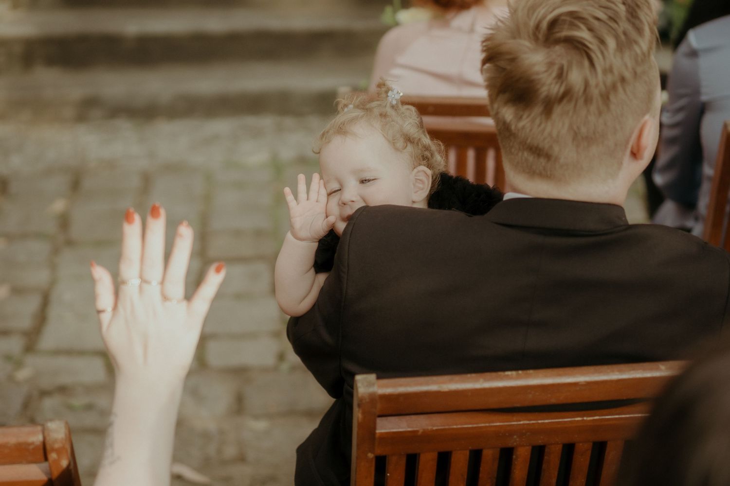 A heartwarming gesture of hands waving during a gathering at a wooden dining table.