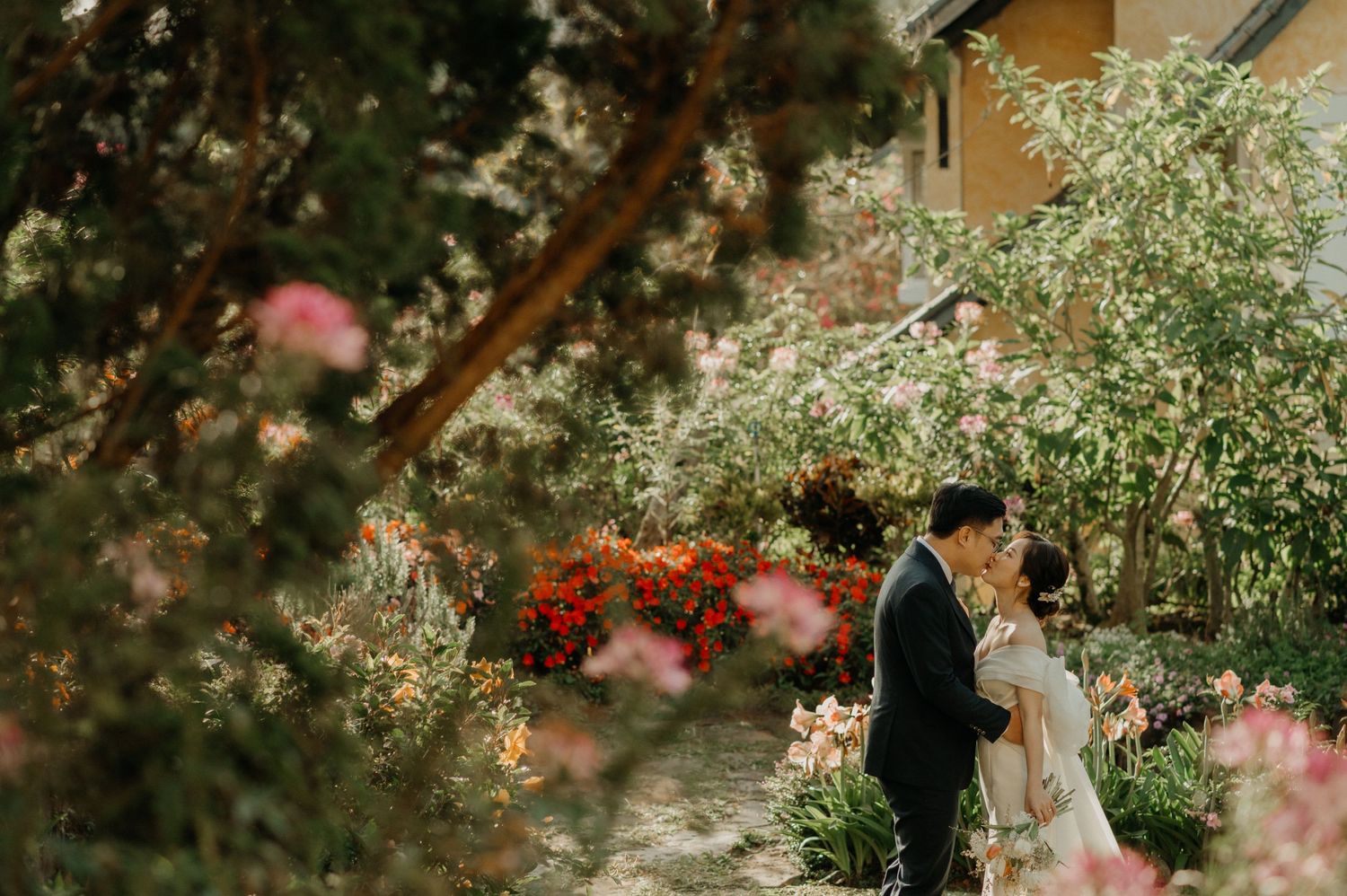 A romantic garden wedding scene with spring blossoms and greenery surrounding a couple in formal attire.