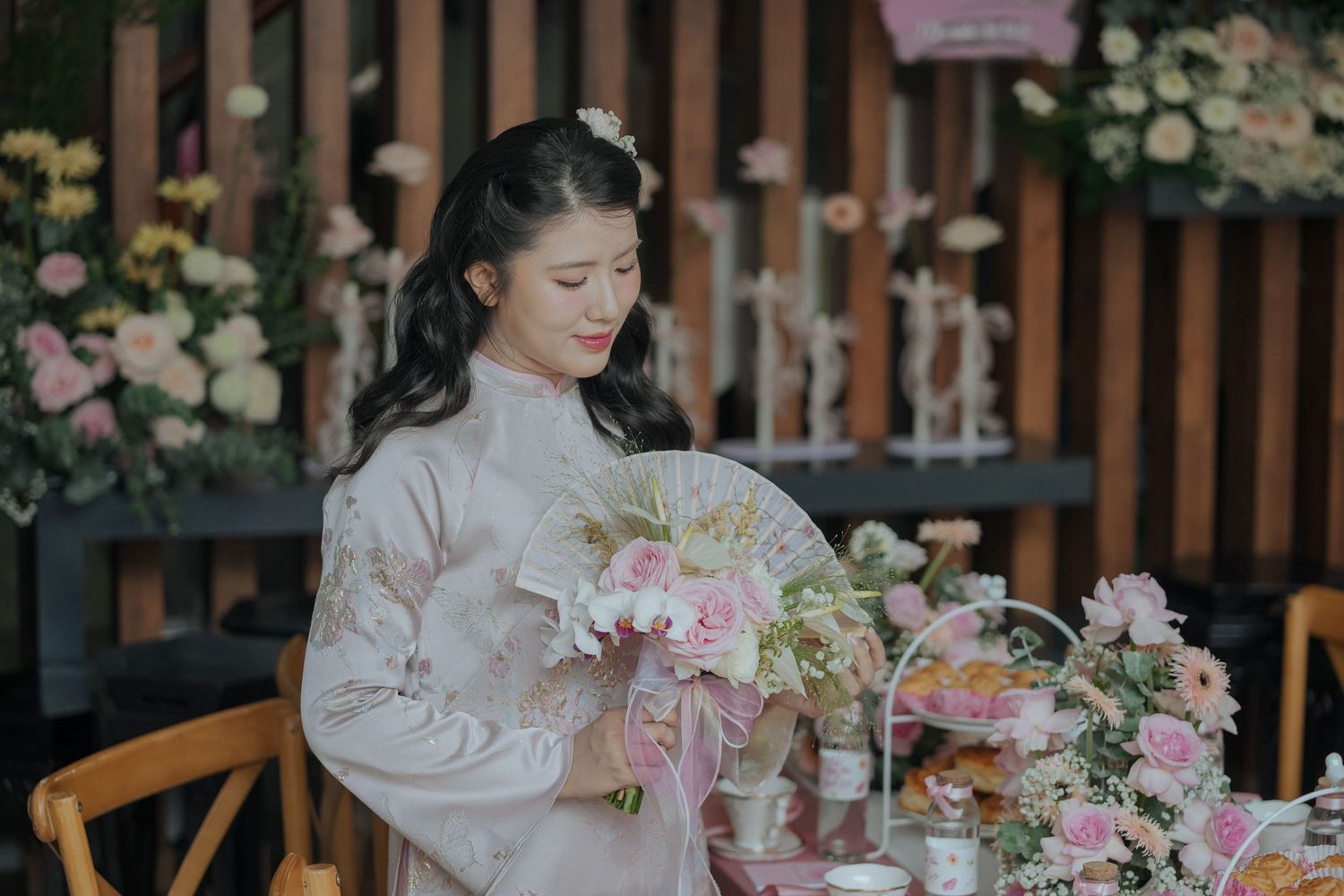 Traditional tea ceremony with pink floral arrangements and wooden furniture.