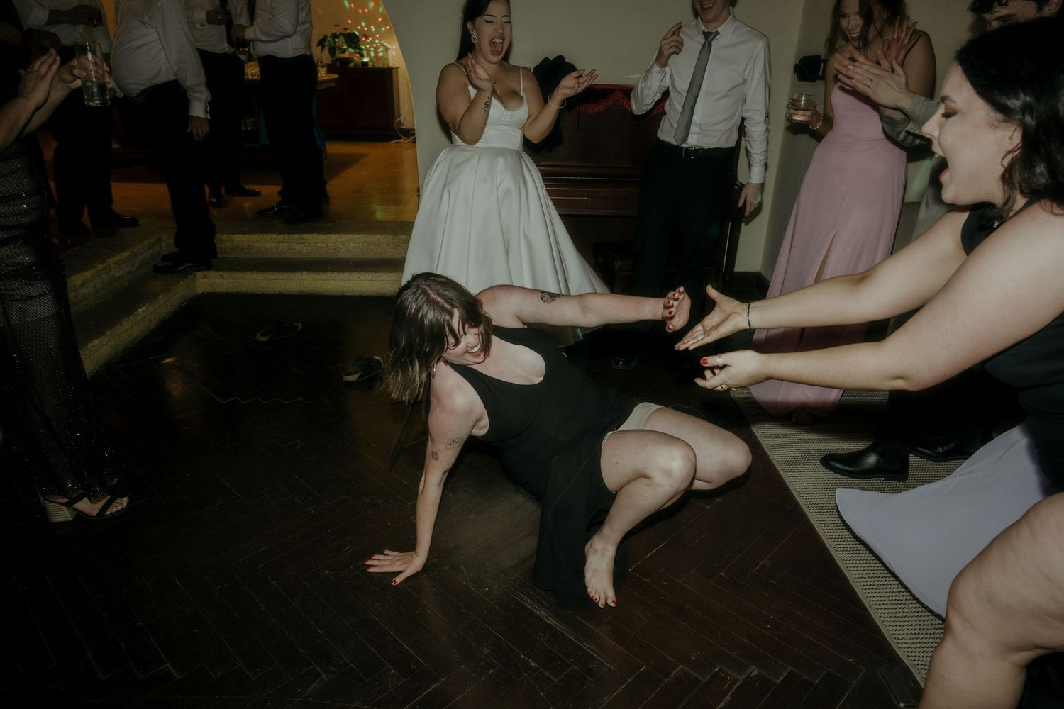 Guests show off dance moves and get low on the dance floor during what appears to be a wedding reception celebration.