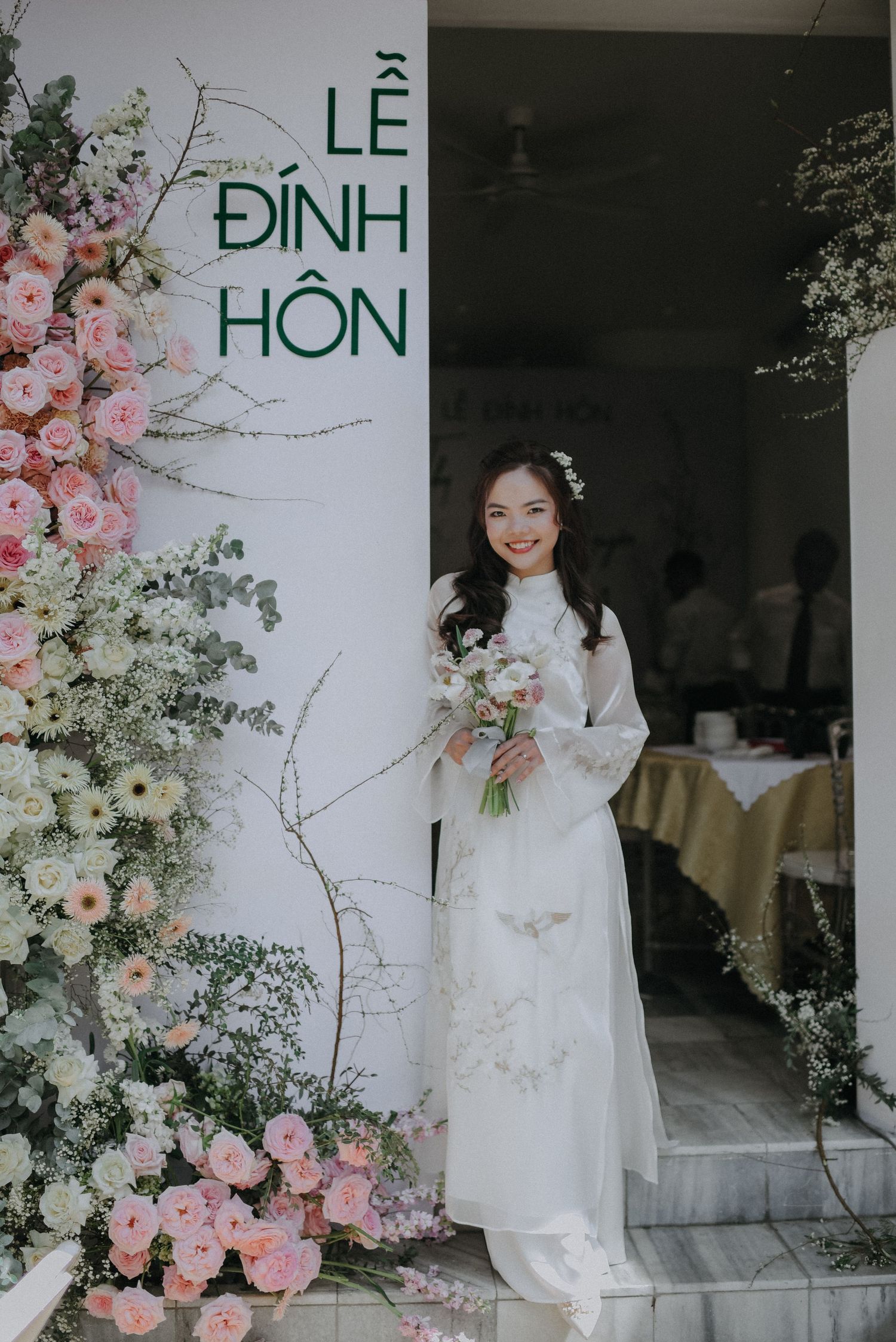 Traditional Vietnamese wedding ceremony setup with pink floral arrangements and elegant signage.