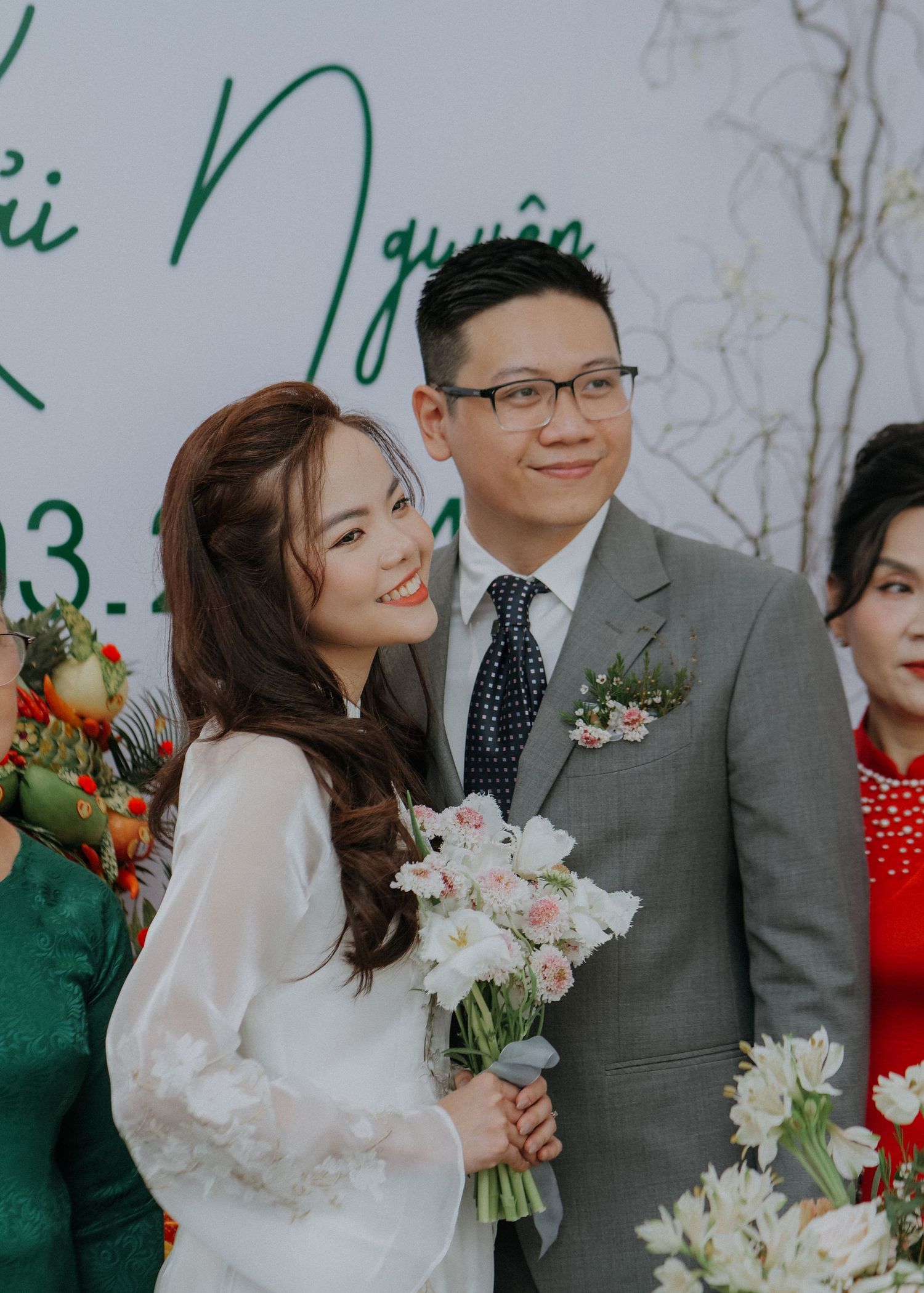 Traditional Vietnamese wedding ceremony with couple surrounded by colorful florals and decorations.