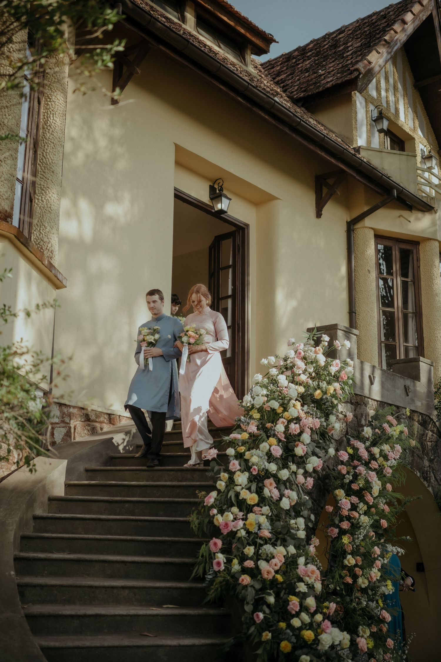 A romantic scene on the steps of a rustic cottage with blooming rose bushes and vintage architectural details.