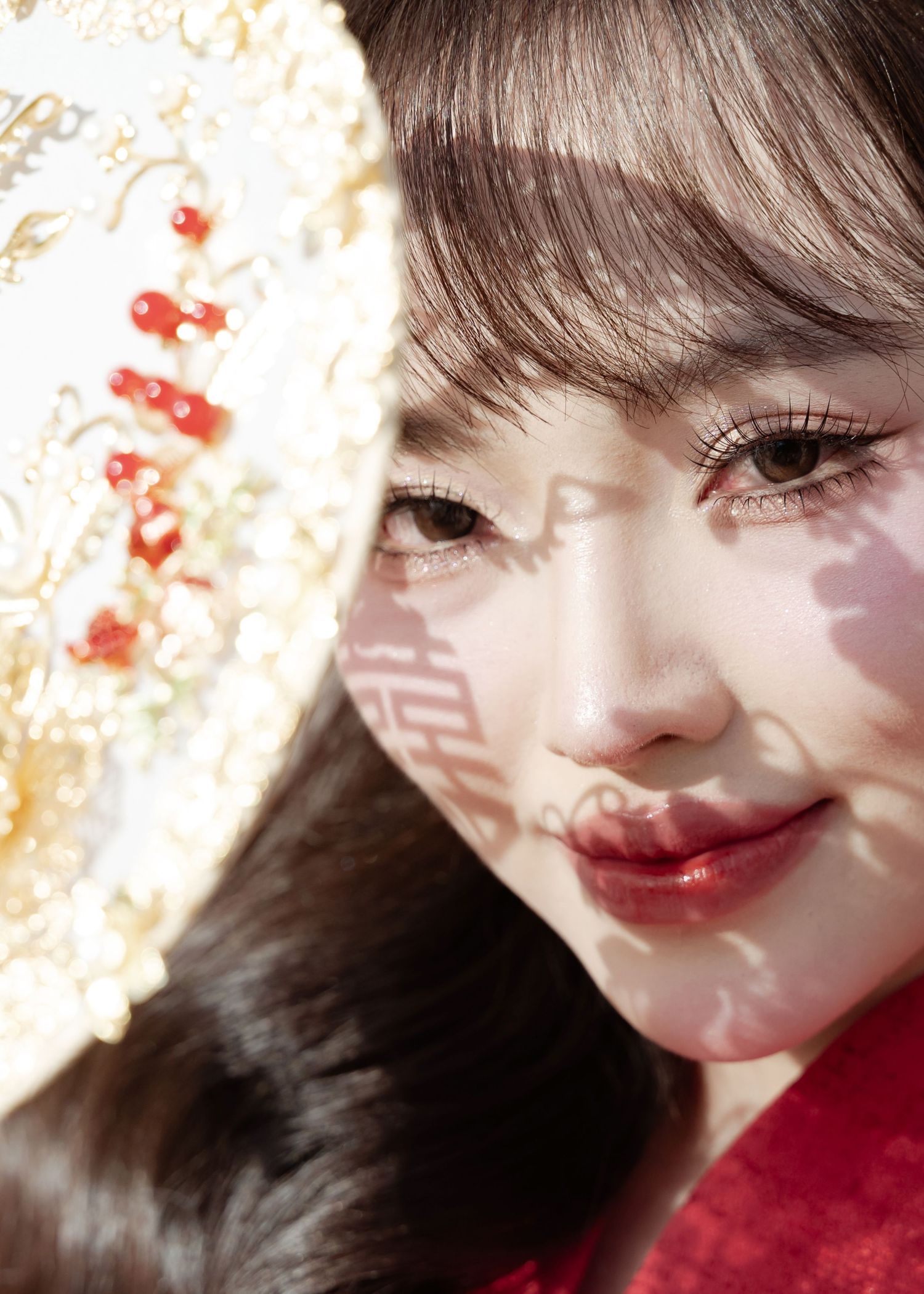 Close-up portrait with red lipstick and Chinese lantern casting soft shadows in warm lighting.