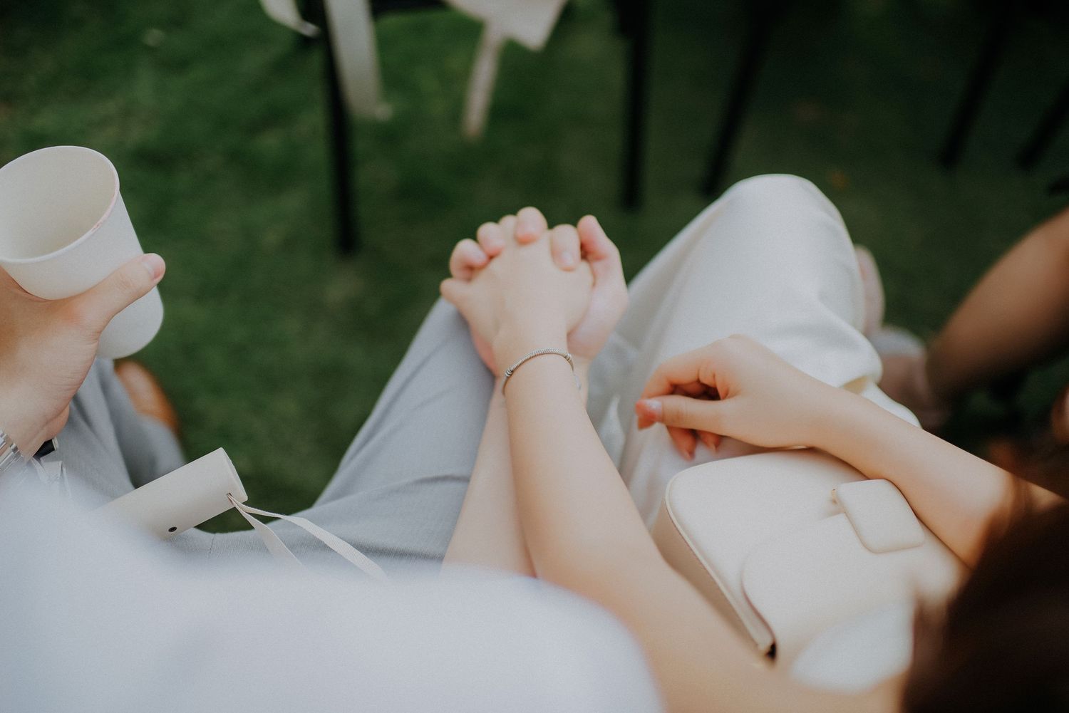 Close-up of clasped hands resting on white fabric during intimate wedding moment.