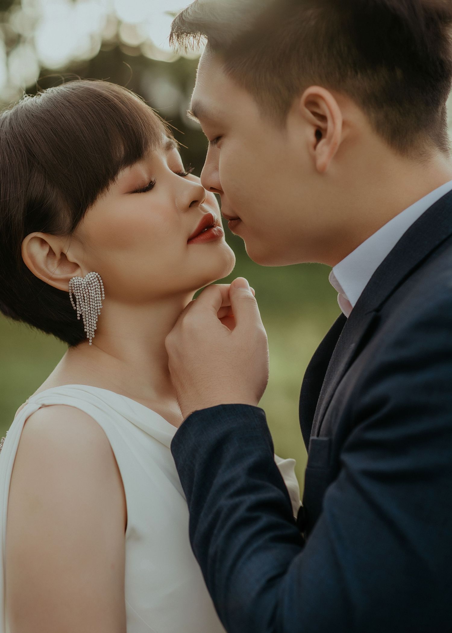 Romantic close-up of couple in wedding attire sharing an intimate moment outdoors with soft bokeh lighting.
