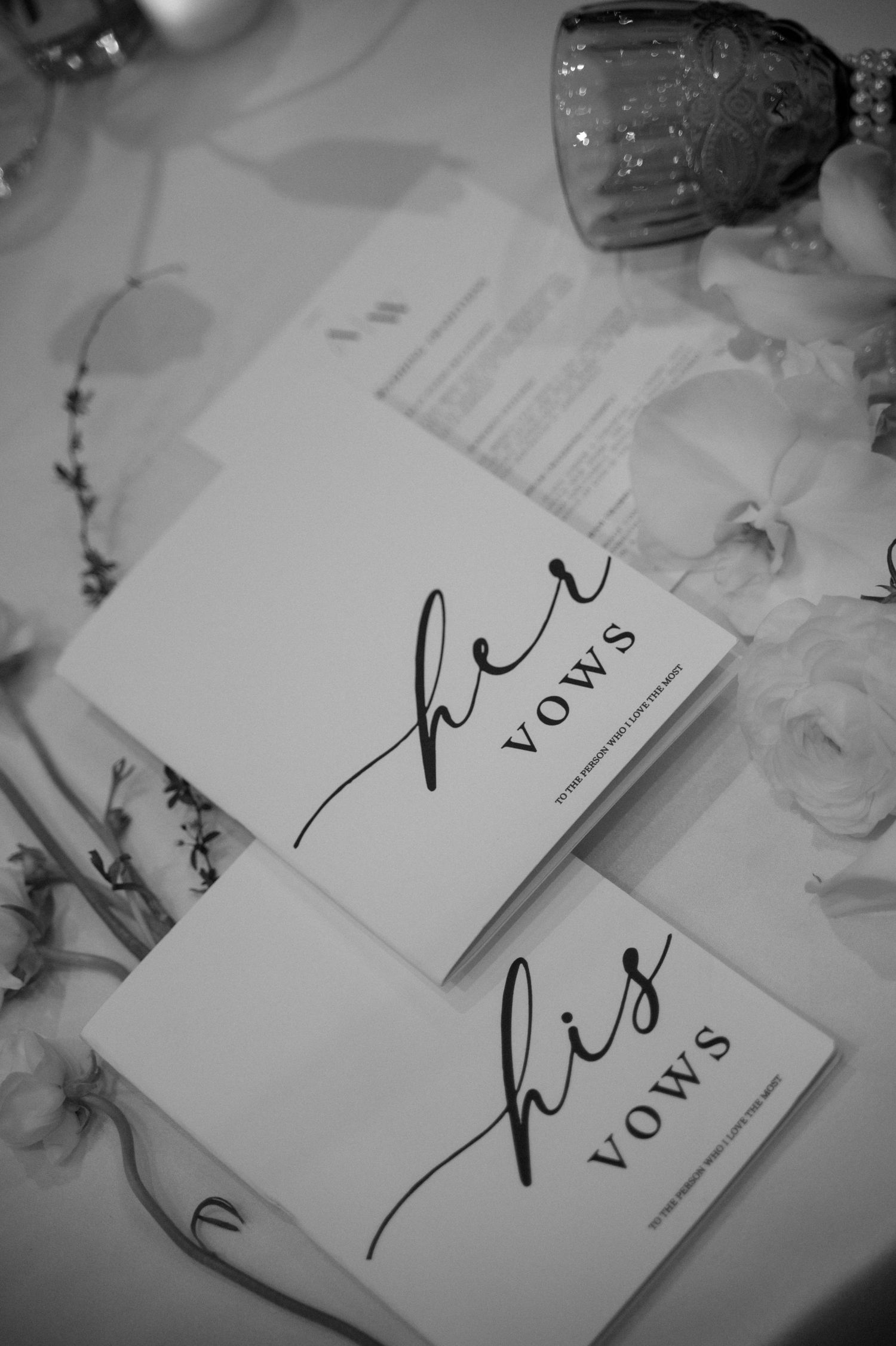 Black and white wedding vow books displayed on a table with elegant calligraphy.