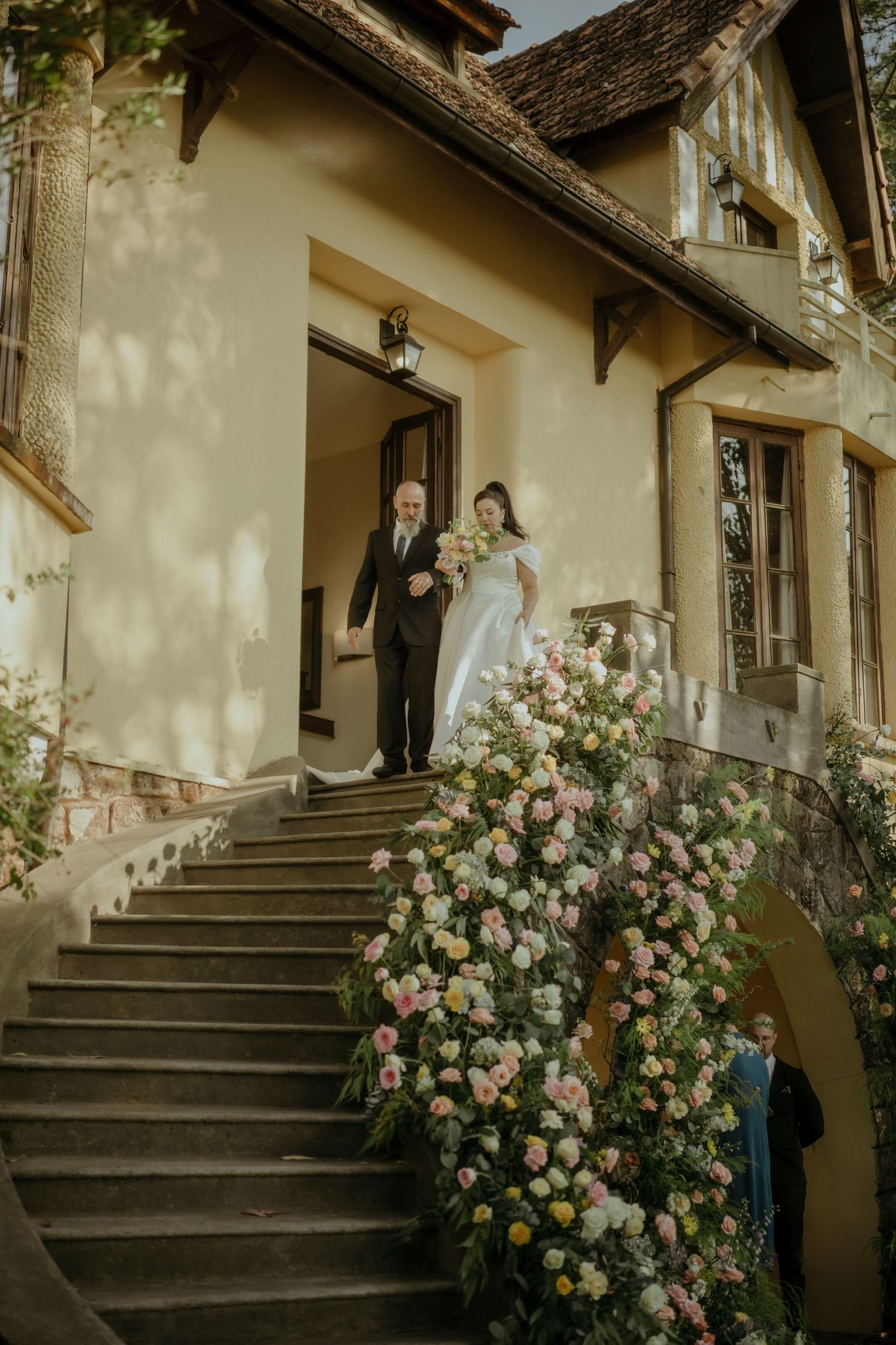 Elegant staircase entrance to a vintage home adorned with climbing pink roses and stone steps at twilight.