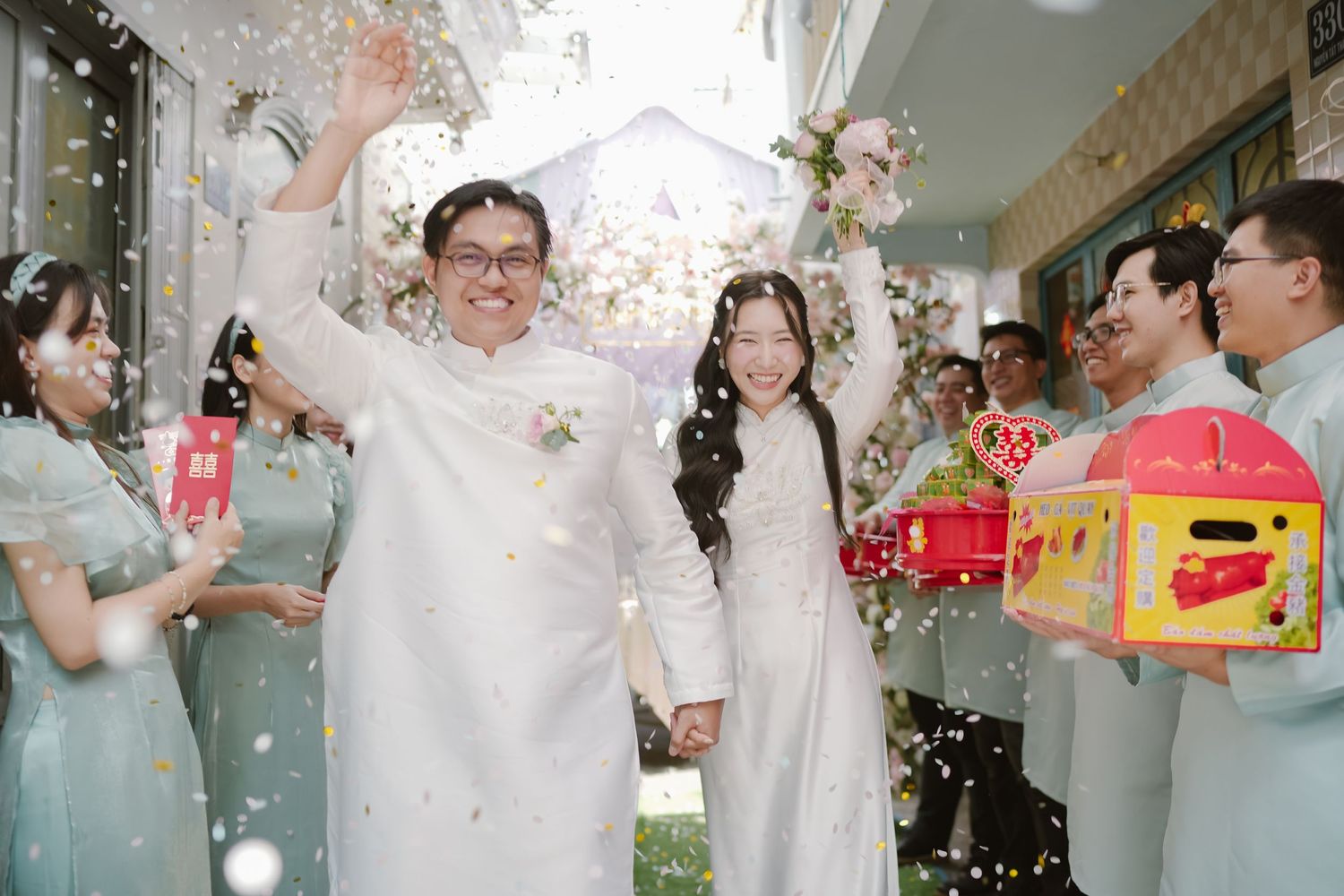 Wedding party showering couple with confetti while exchanging red and yellow gifts.