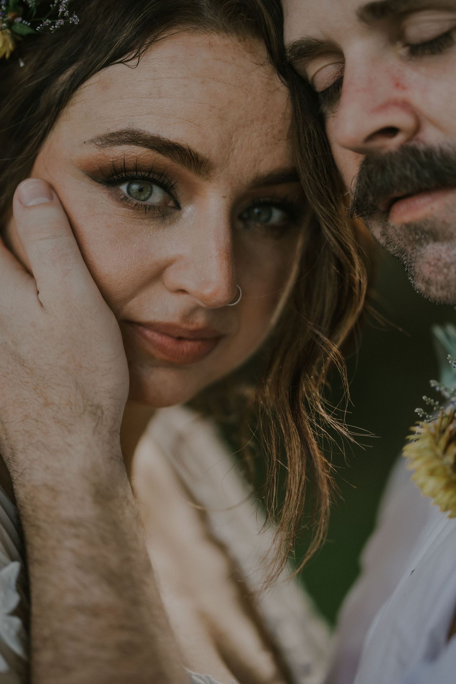 Close-up romantic wedding portrait showing intimate moment between couple with floral accents.