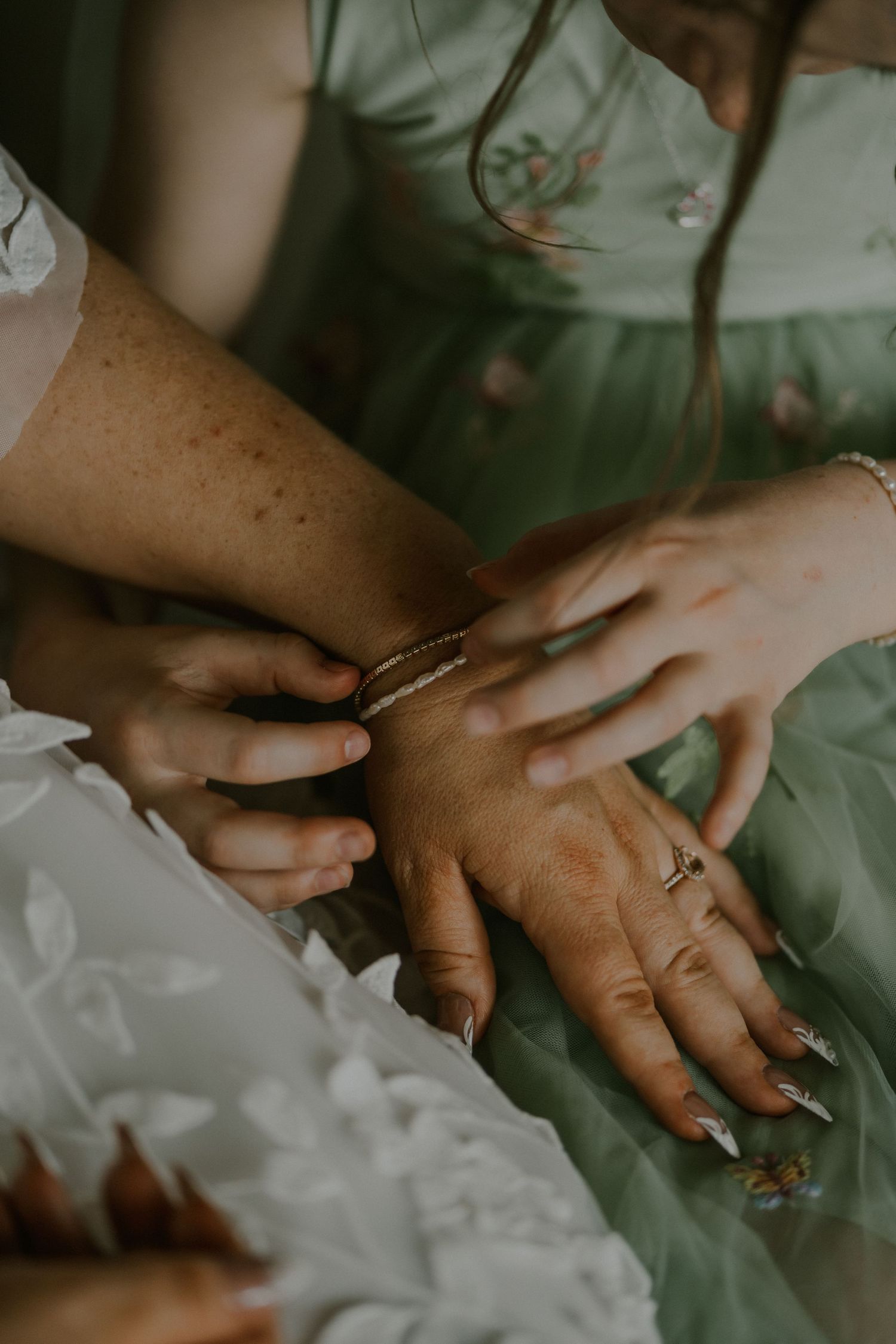 Close-up shot of hands adjusting jewelry against a light green background.