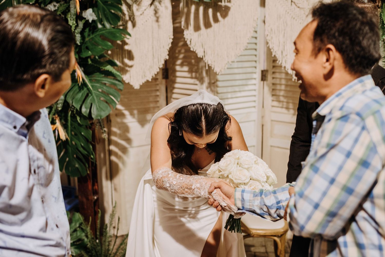 Wedding moment captured with tropical foliage and macrame backdrop.