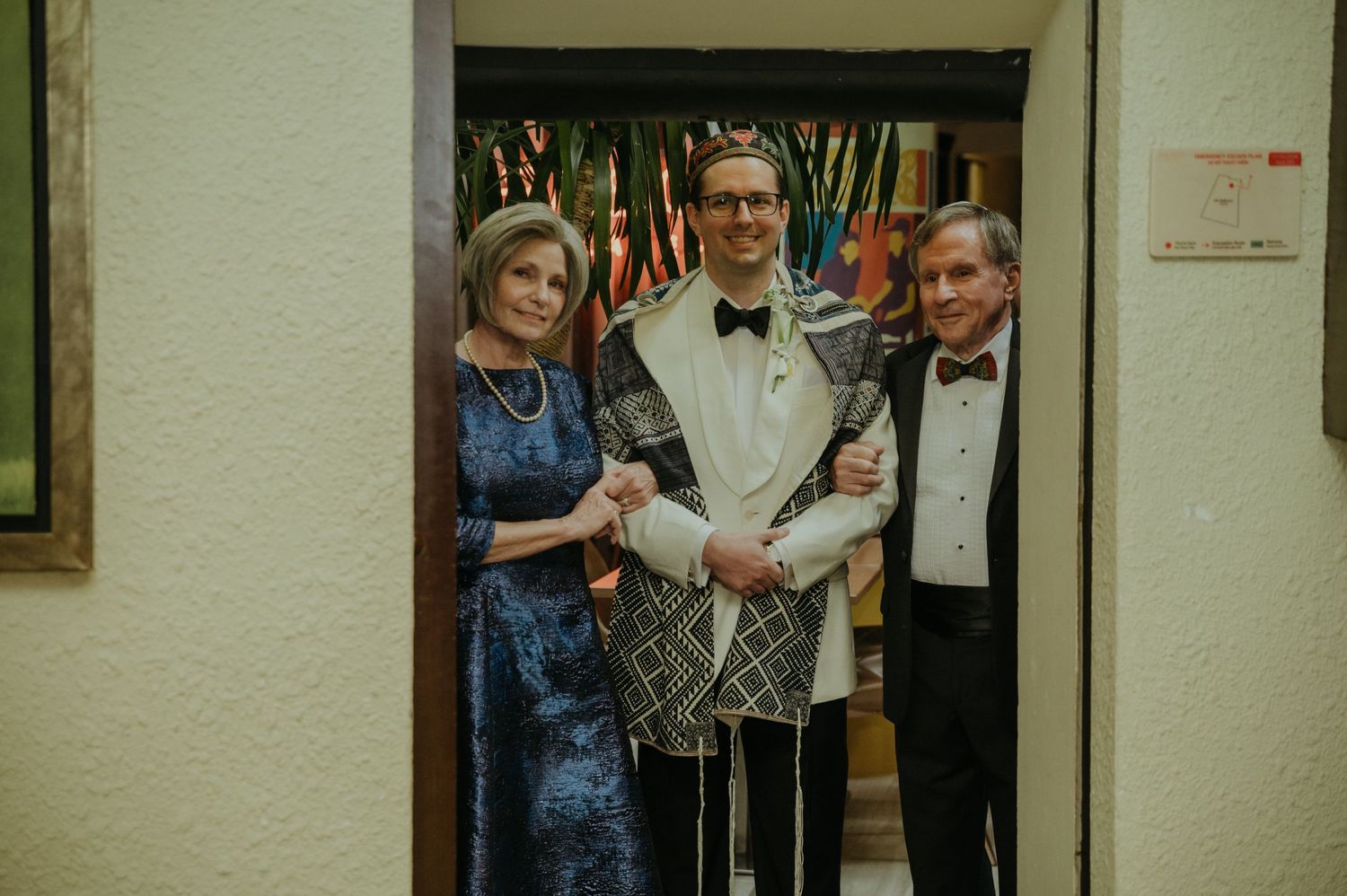 Formal gathering in a doorway with attendees wearing elegant evening attire.
