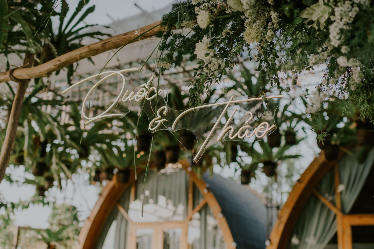 Decorative hanging greenery and floral arrangements beneath a glass ceiling.