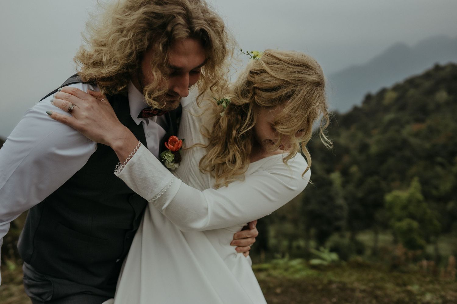 A romantic wedding couple embracing on a mountainside in an intimate moment.