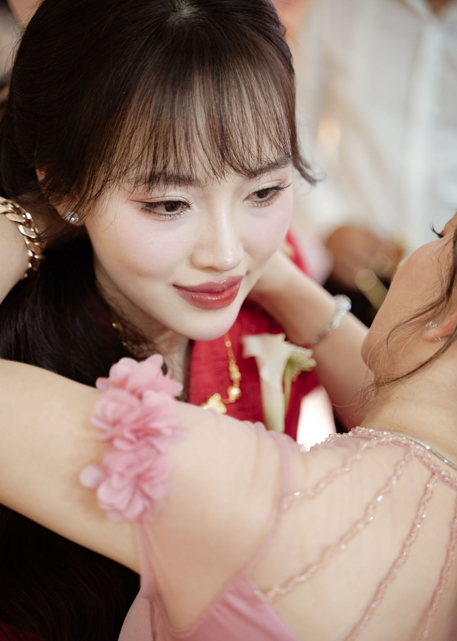 Someone wearing a red traditional dress with a pink floral corsage at a formal event.