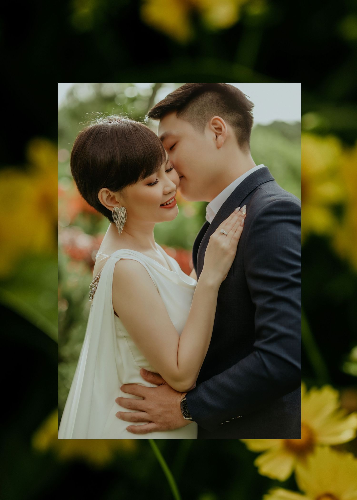 A romantic wedding portrait of a couple embracing outdoors with yellow flowers in the background.