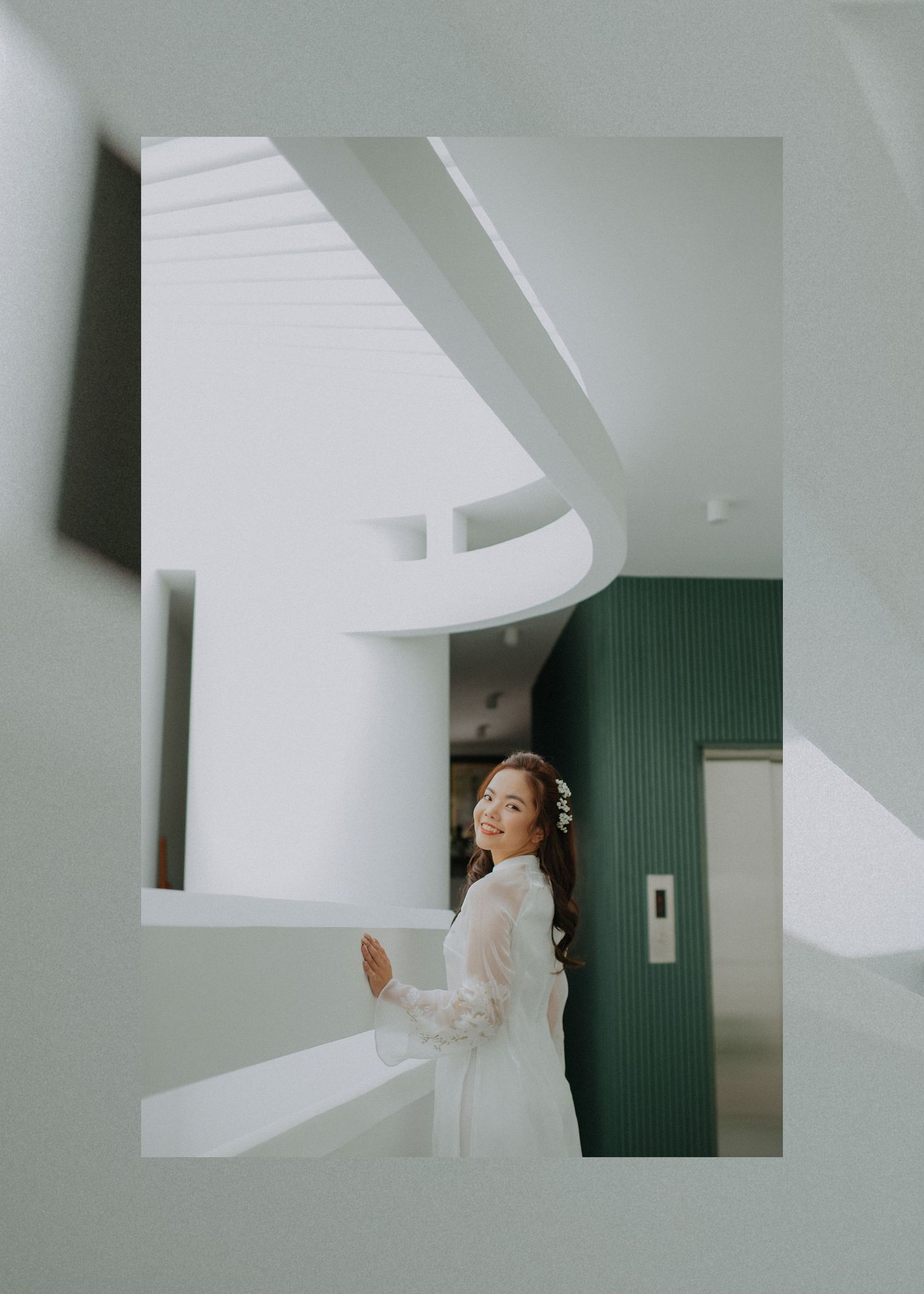 Artistic architectural shot of bride in white dress against modern white and green interior.